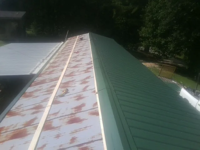 Old rusted panels beside newly installed green metal roofing — Wind Damage Roof Repair by Roofing Brothers in New Canaan