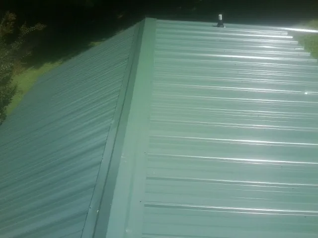 New green metal panels meeting at the ridge of a roof — Flat Roof Repair work by our crew in New Canaan