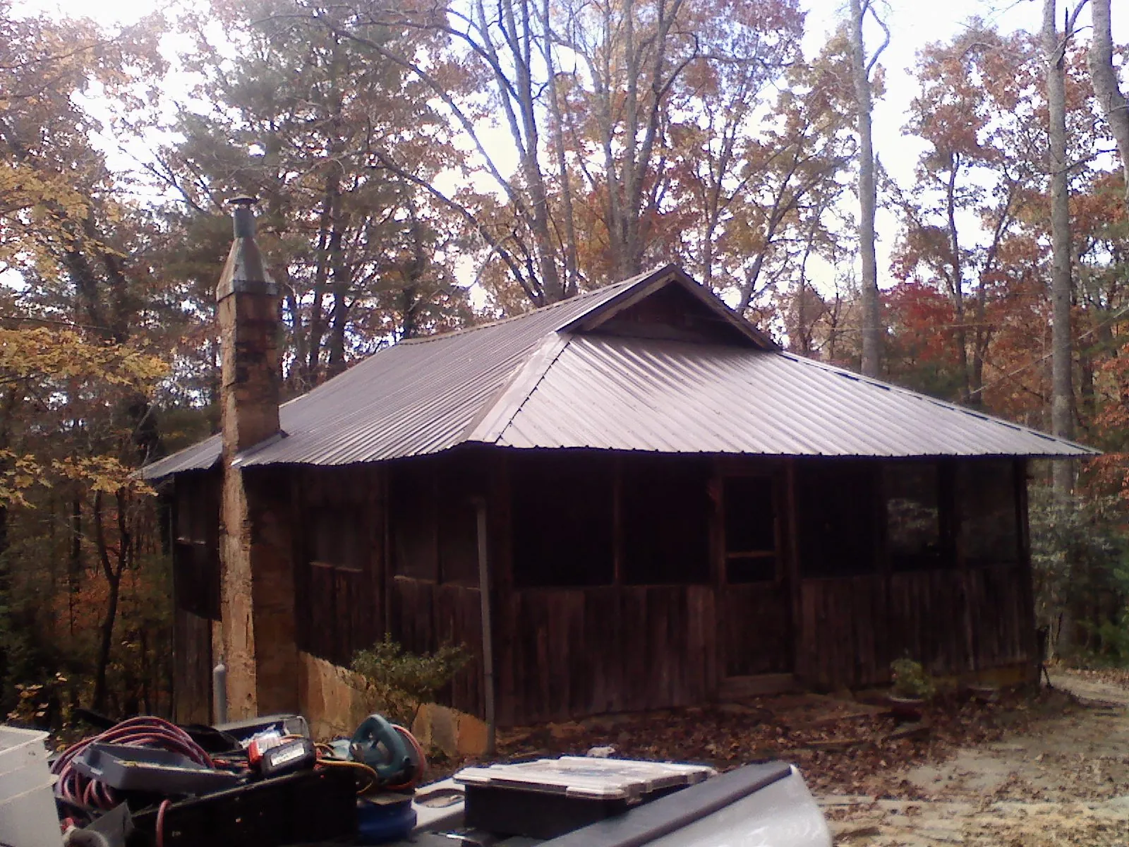 Brown metal hip roof on an old cabin with a stone chimney in New Canaan