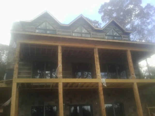 Dormers and porch framing on a large log home under construction — Roof Coating work by our crew in New Canaan