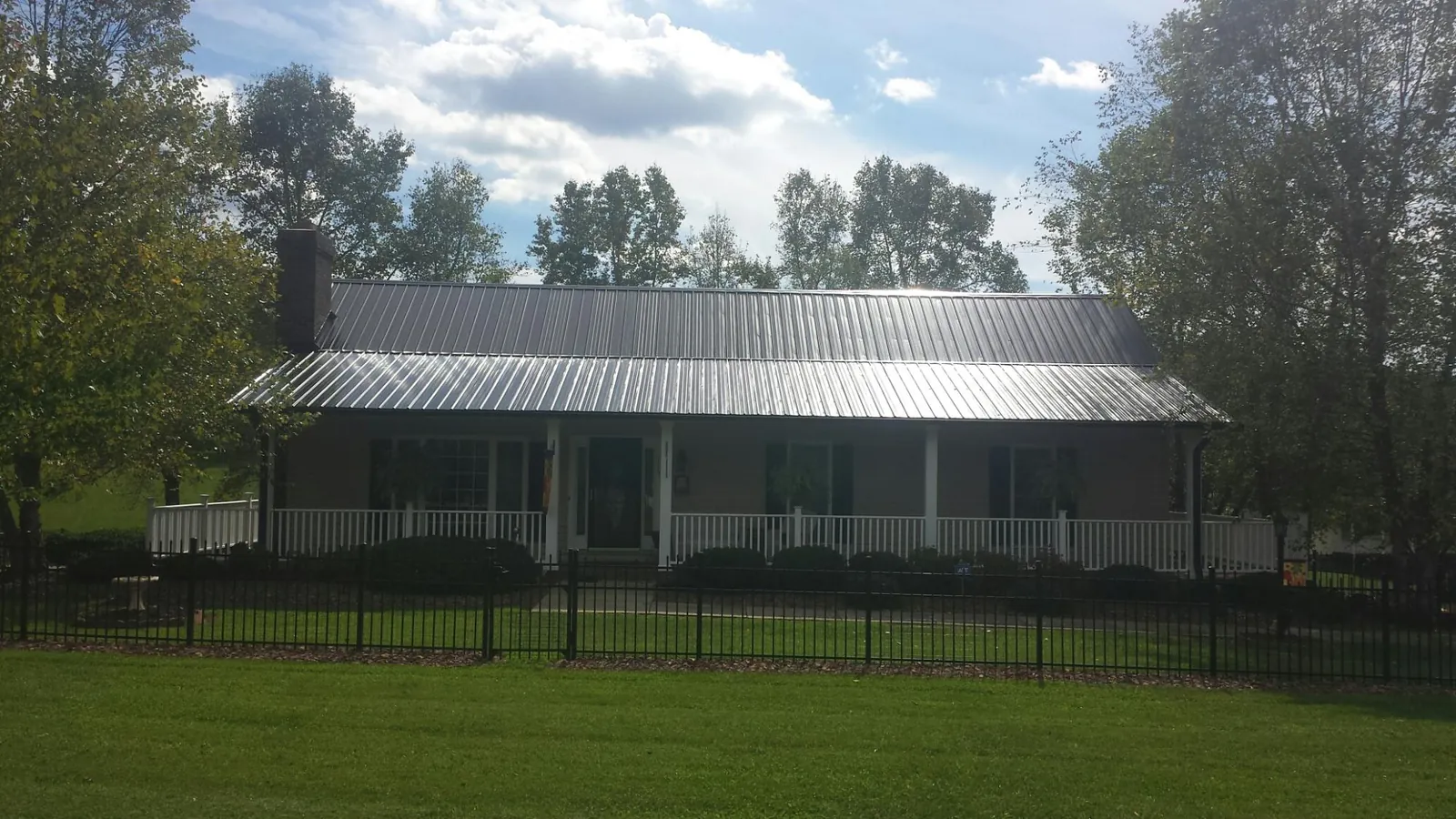 Gray metal roof on a brick ranch with a full width front porch — Gutter Guard Installation work by our crew in New Canaan