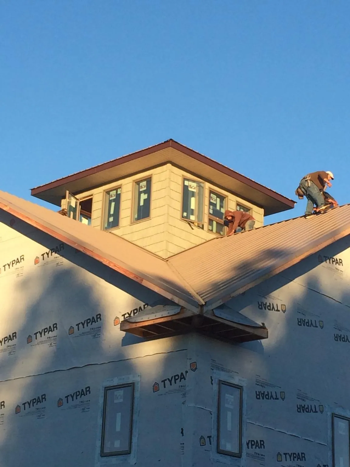Roofers working around a rooftop cupola on a new metal roof at sunset — Roof Waterproofing in New Canaan by Roofing Brothers